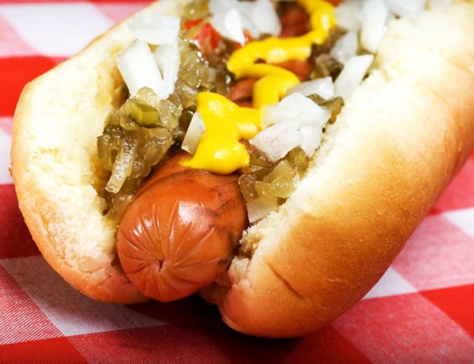 A hot dog with mustard, relish and onions on it.