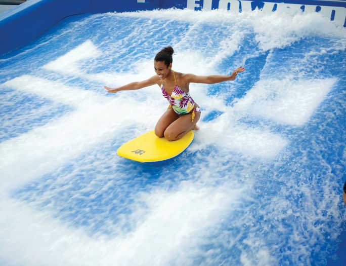A woman riding on top of a wave in the water.