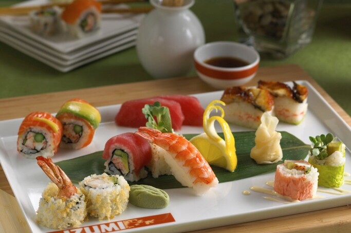 A plate of sushi and other food on the table.