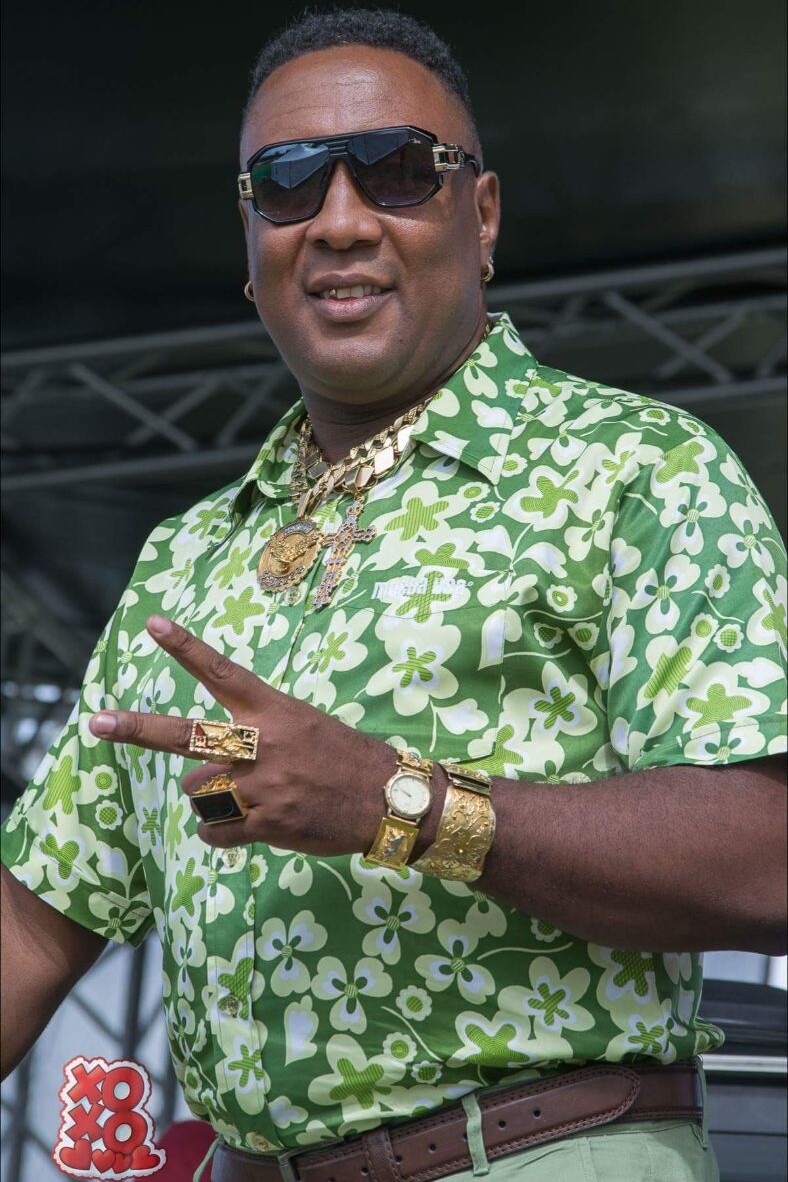 A man in green shirt and gold jewelry.