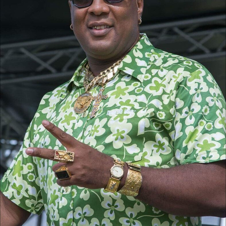 A man in green shirt and gold jewelry.