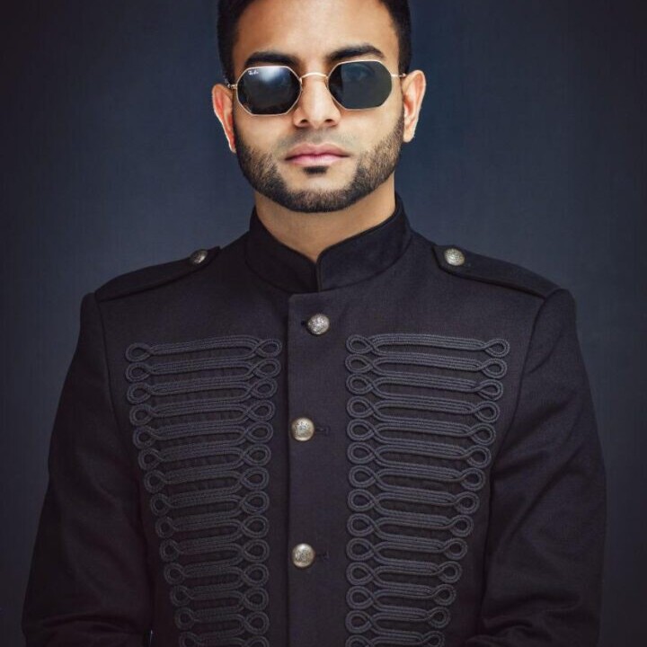 A man in black jacket and sunglasses posing for the camera.