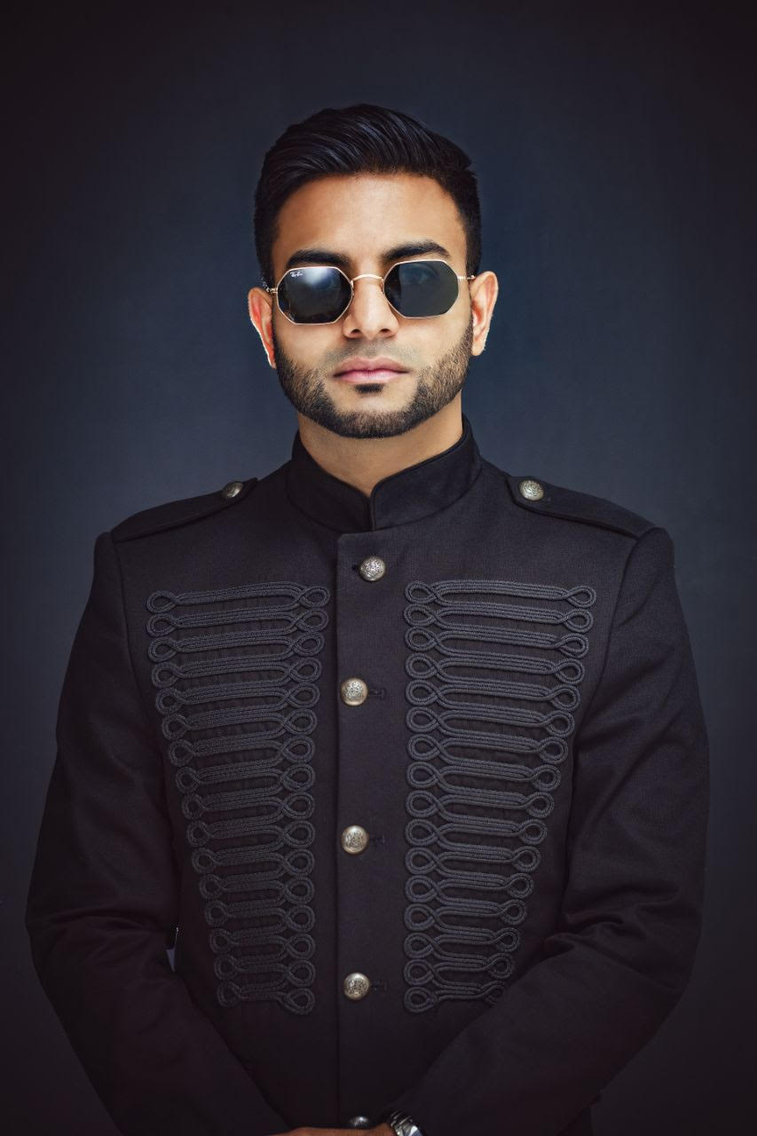 A man in black jacket and sunglasses posing for the camera.