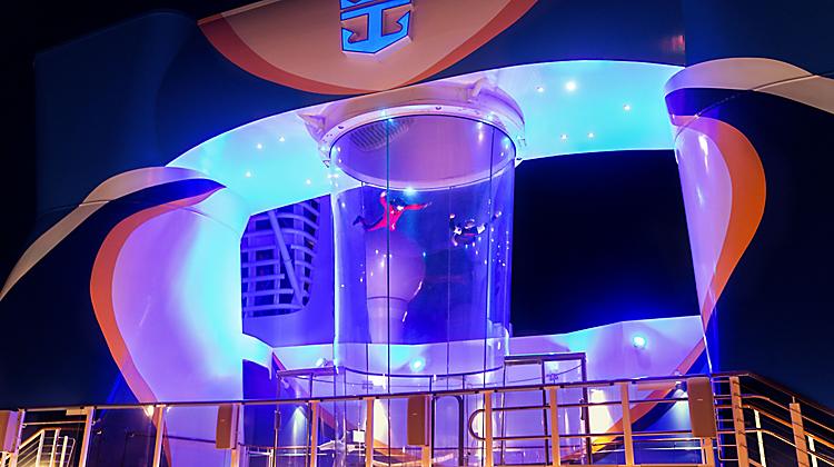 A man is hanging from the ceiling of an indoor skydiving device.