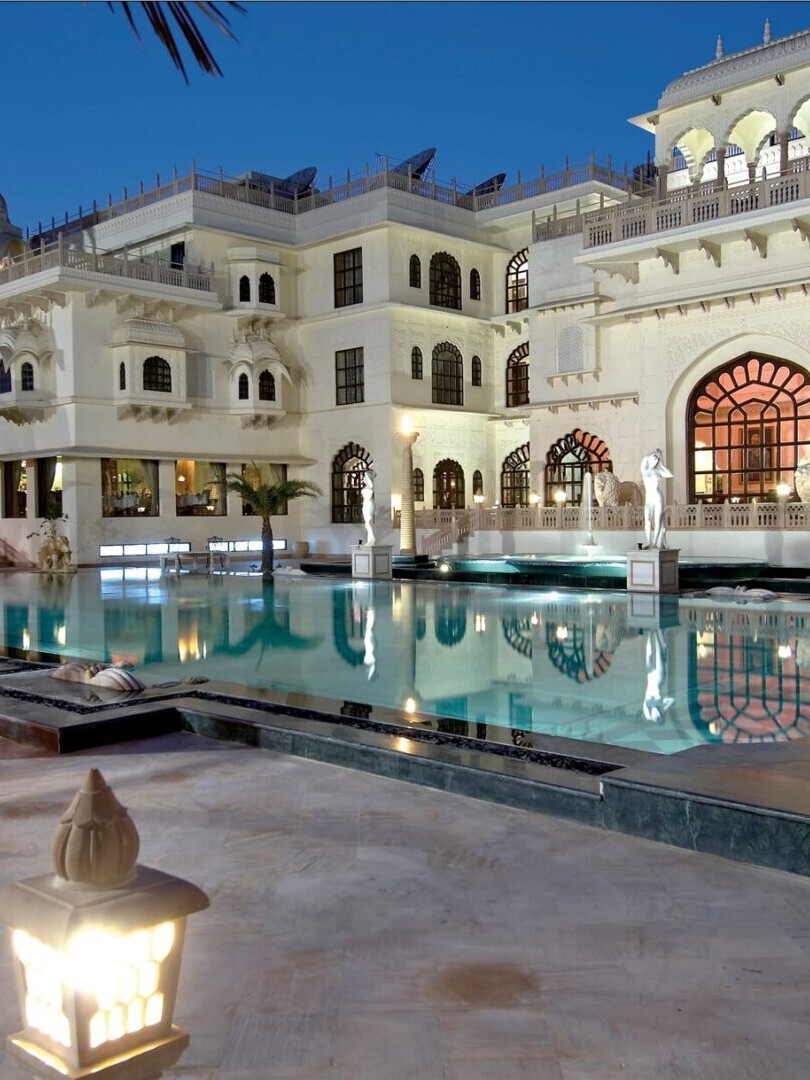 A large pool with a fountain and a castle like building.