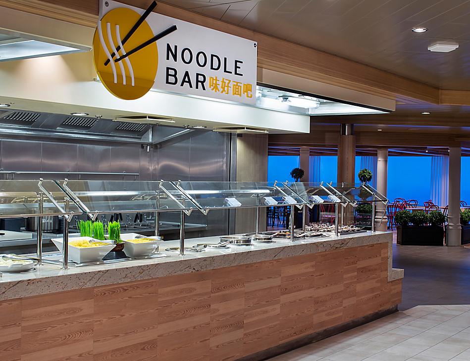 A noodle bar with many bowls of food on the counter.