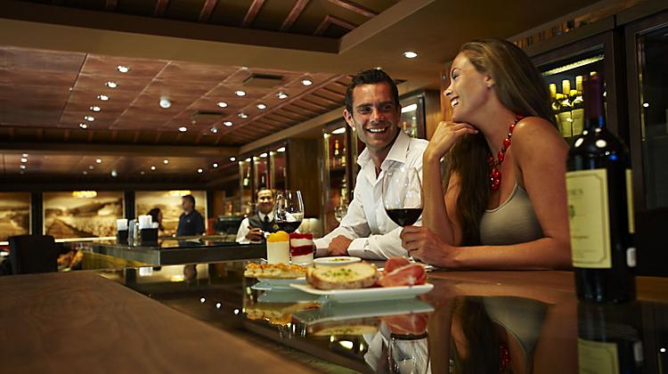 A man and woman sitting at the bar of a restaurant.