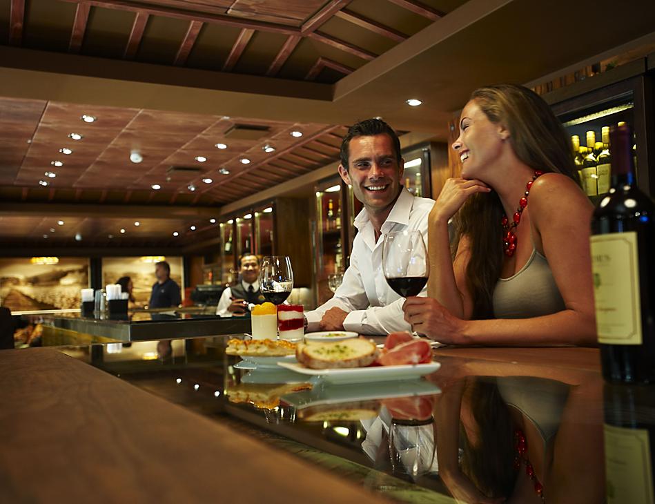 A man and woman sitting at the bar of a restaurant.