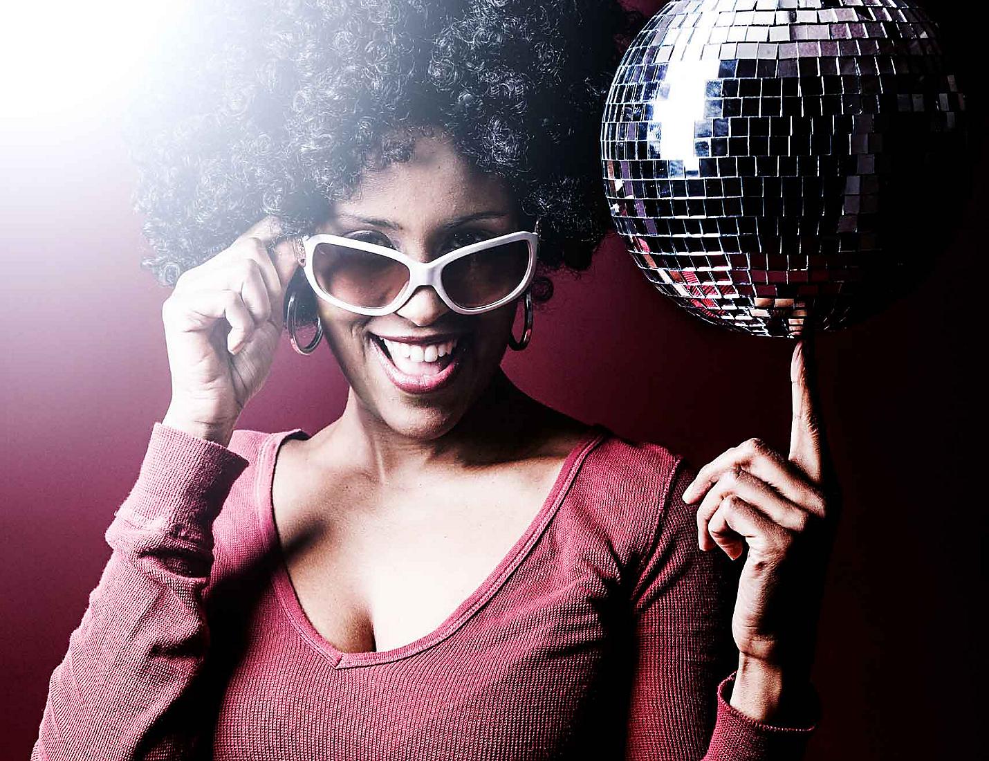 A woman holding a disco ball and wearing sunglasses.