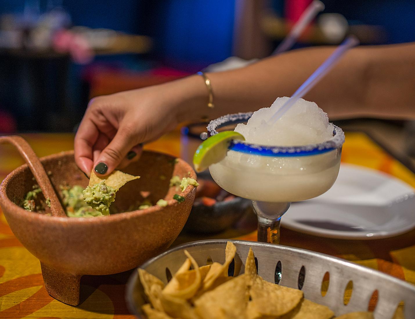 A person is eating guacamole and chips at a table.