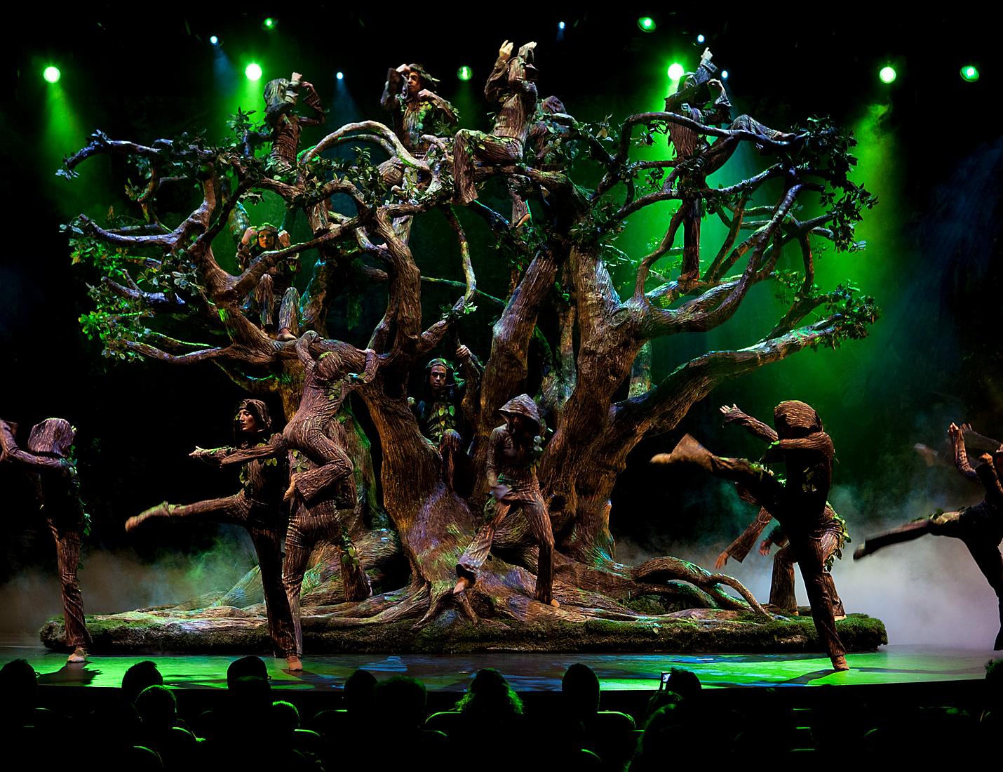 A group of people standing around trees on stage.