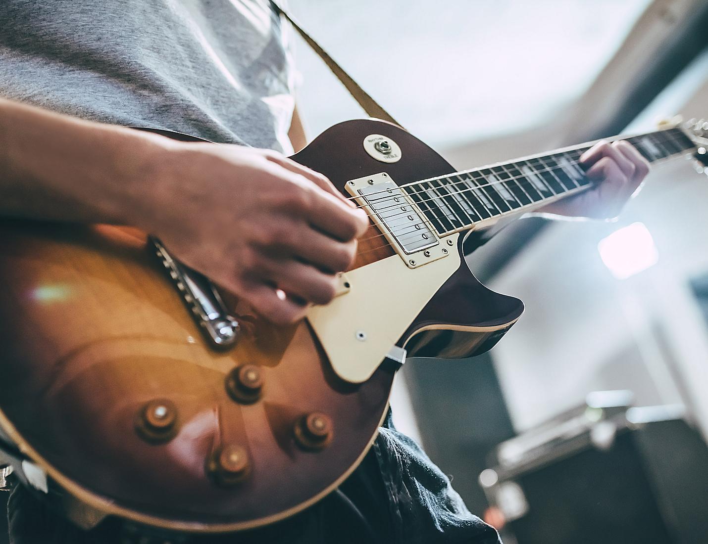 A person playing an electric guitar in front of a microphone.