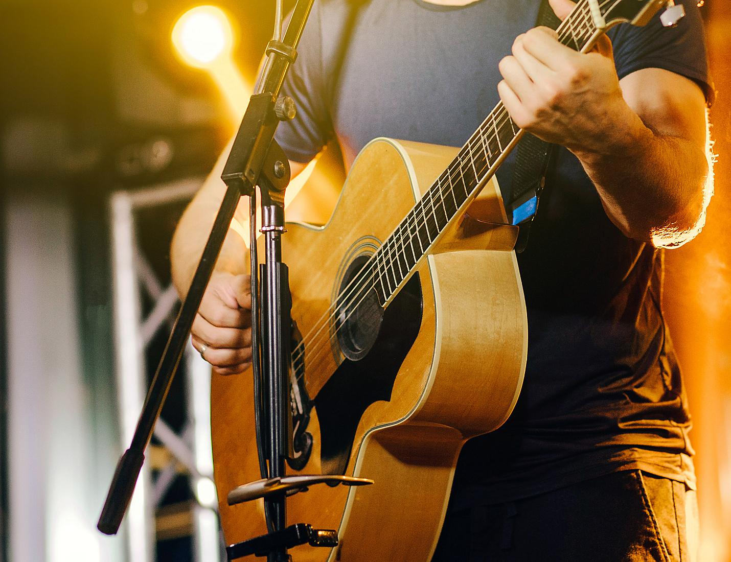 A person playing an acoustic guitar on stage.