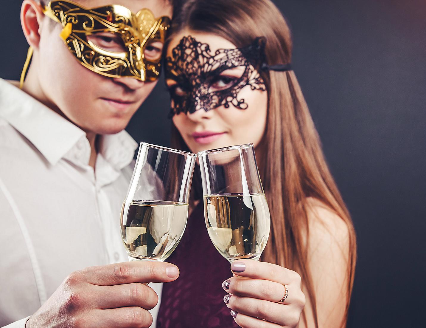 A man and woman holding wine glasses wearing masks.