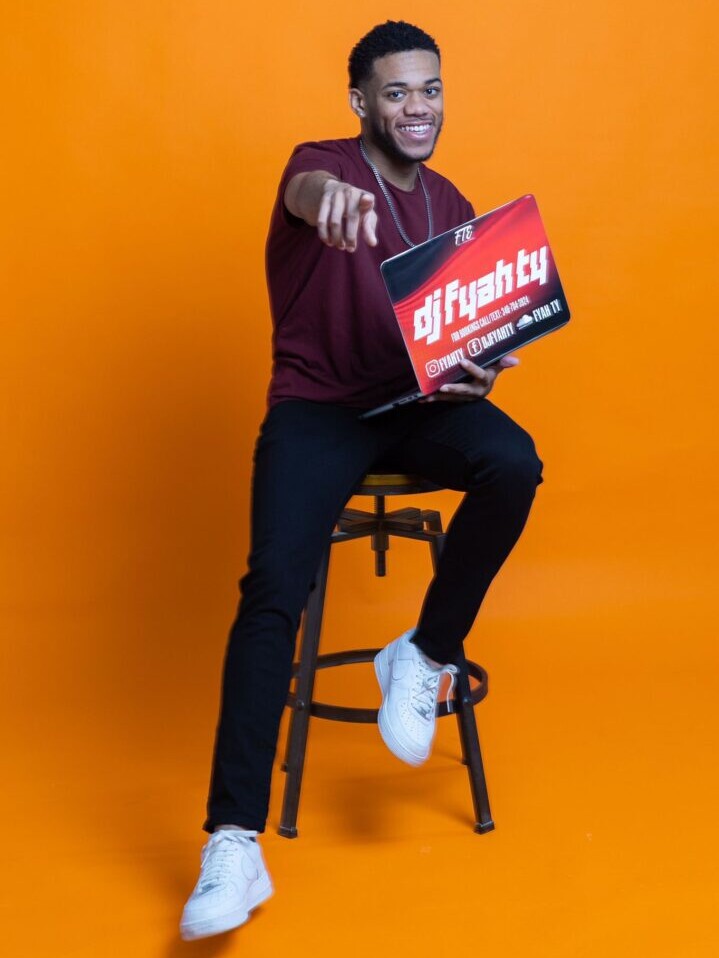 A man sitting on top of a stool holding up a sign.