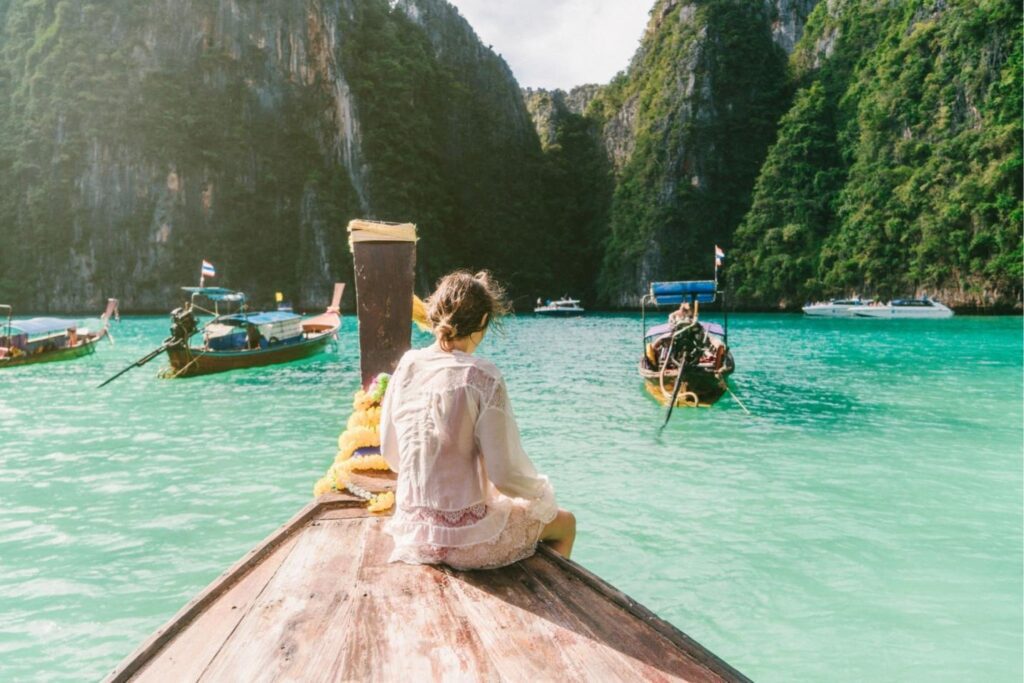 A woman sitting on the back of a boat in the water.