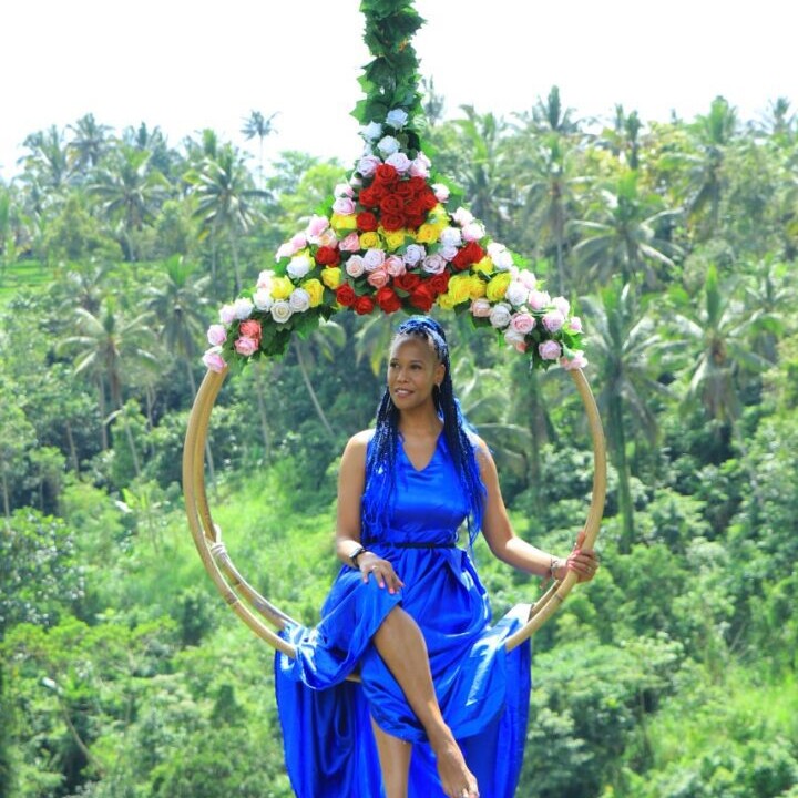 A woman in blue dress swinging on a hula hoop.